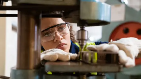 Getty Images Close-up of female apprentice using a machine