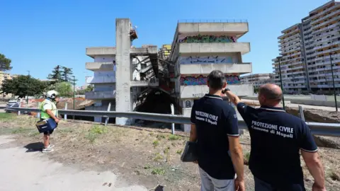 Marco Cantile/LightRocket  Two men from the Civil Protection in front of the building in the Scampia district of Naples