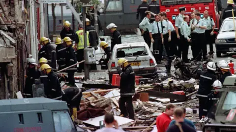 PA Media Emergency services wade through the wreckage caused by the Omagh bomb in 1998