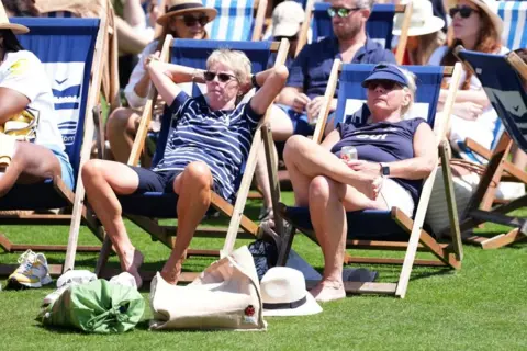 PA People sunbathing in deckchairs