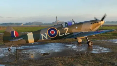 AAIB A kit-built replica Spitfire standing on a runway on a ckear day with its propeller turning