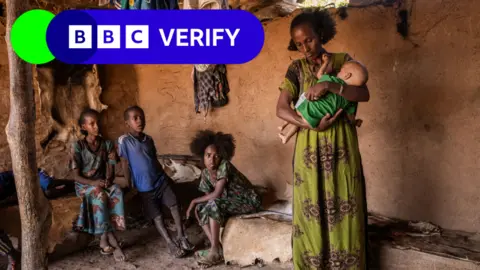 Ed Ram/Getty A mother holds her baby in a room with her family in Tigray