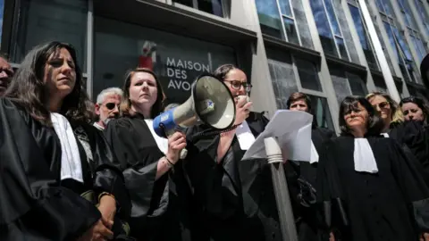 OLIVIER CHASSIGNOLE/AFP Vice-President of the Lyon Court Bar Sarah Kebir (C) delivers a speech with a megaphone