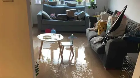 Water covering the living room floor and items on the sofa for safe keeping