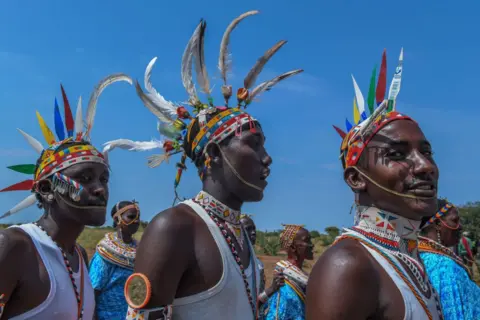 GERALD ANDERSON / GETTY IMAGES Three men from the Rendille community wearing brightly beaded jewellery and feathered headdresses. 