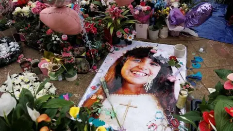 Reuters Floral tributes, balloons and friendship bracelets at a Southport tribute featuring an image of Alice