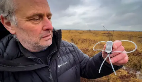 Tony Cross holding a GPS tracker