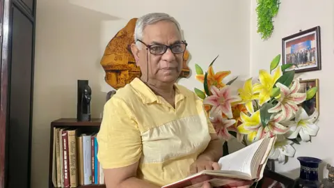 Former Bangladeshi diplomat Maroof Zaman who was abducted by Bangladeshi forces holding a book