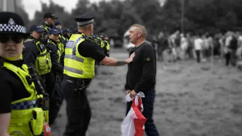 PA Media A man with a flag next to police