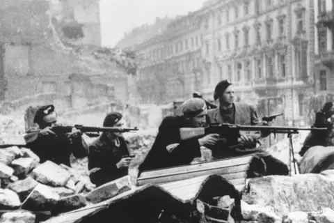 Getty Images Black and white photo of Polish troops with guns surrounded by rubble in Warsaw