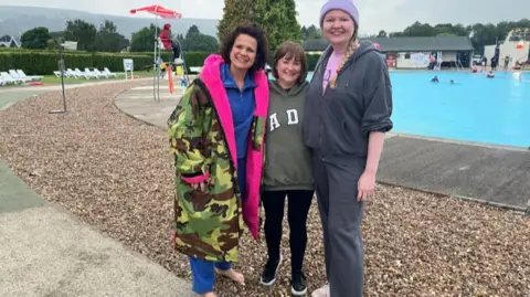 Julia Bryson/BBC Jen McKenna with two female friends stood in front of the lido 