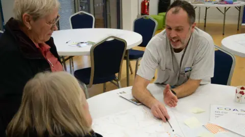 North Norfolk District Council Rob Goodliffe sat at a table with two women looking at detailed plans