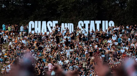 Sam Neil Chase & Status logo in the crowd