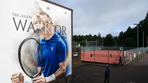 PA Media A 20ft mural of Andy Murray holding a tennis racket with his hands grasped and mouth opens. It reads Sir Andy, warrior, legend.