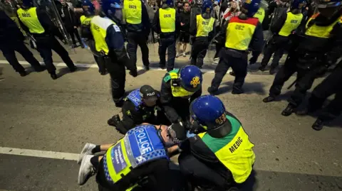 Getty Images :Police officers detain some far-right protesters after they tried to cross to the side of the opposing group in Plymouth