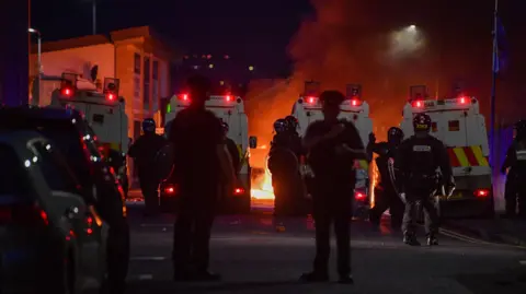 Pacemaker Riot police on Donegall Road with fire in background