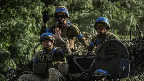 Reuters Three Ukrainian soldiers sit on top of tank in Sumy region