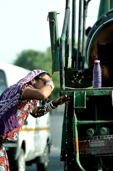 Prerna Jain A woman cools herself from a roadside water tap