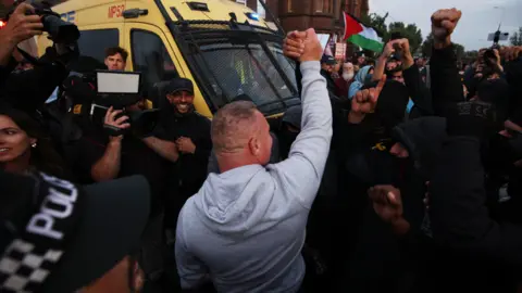 Getty Images A man who reportedly said to the protesters he was on neither side of the protests, but agreed with some of the issues on both sides, gestures to the crowds and is cheered on