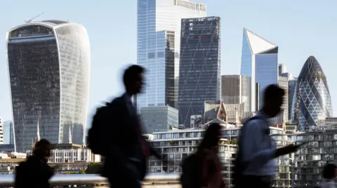 Getty Images Blurred motion photo of incidental business people walking to work with view of the financial district behind