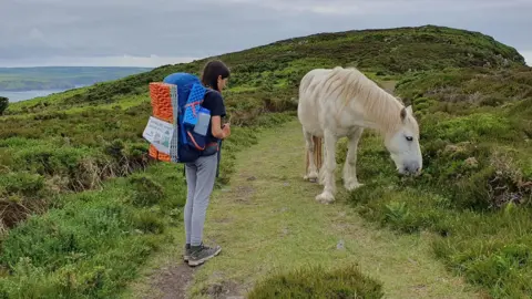 Kerry-Anne Finn on a path with a wild pony