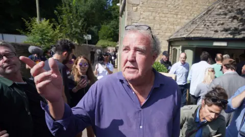 PA Media Jeremy Clarkson stands outside his new pub surrounded by crowds. 