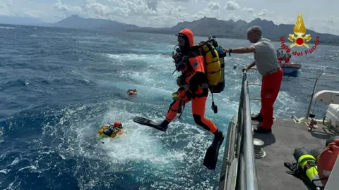 Reuters Divers operate in the sea to search for the missing yacht passengers