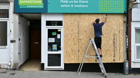 Getty Images A Samaritans charity shop is boarded up in Westcliff a suburb of Southend, as people protect their property in preparation for more unrest on 7 August