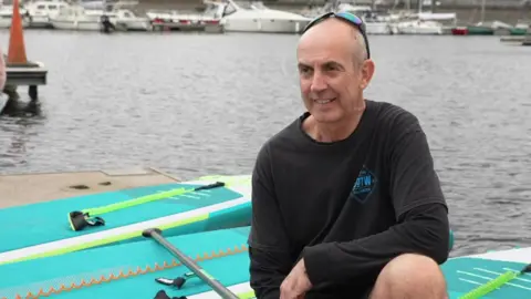 Gareth Stevenson sat on a paddleboard smiling