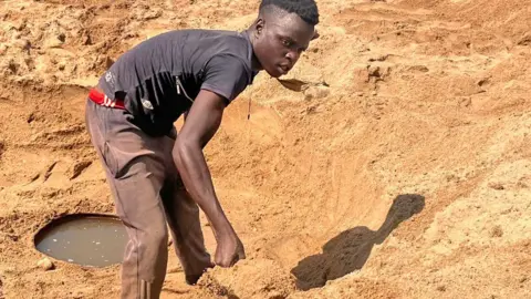 BBC A man digs for water in a riverbed in Kurima village, Zimbabwe