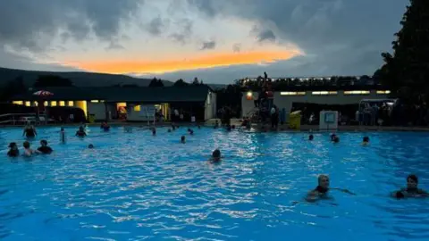 Ilkley Pool and Lido Community Group Swimmers in the outdoor pool at dusk 