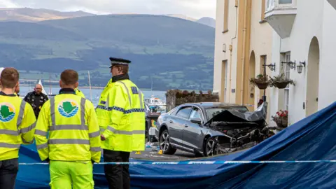 Rob Formstone Freelance Photos North Wales The crash scene on Alma Street, with a badly damaged Audi car near houses, and emergency services officers, including police near a sheet around the scene