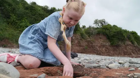 BBC Tegan looks at the dinosaur footprint she uncovered on a south Wales beach during a walk with her mum