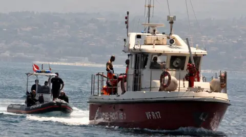 Alessandro FUCARINI/AFP Divers of the Vigili del Fuoco, the Italian Corps of Firefighters, enter Porticello harbor near Palermo, with the body of Hannah Lynch, the last missing person, at the back of the boat on 23 August 2024