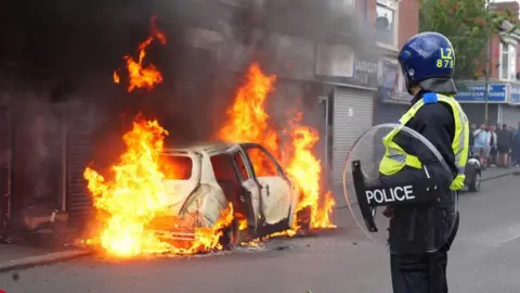 PA Media A car burns on Parliament Road, in Middlesbrough, during an anti-immigration protest.