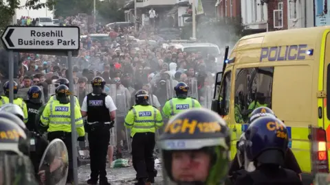 Getty Images Police in riot gear facing a crowd of protestors in Southport