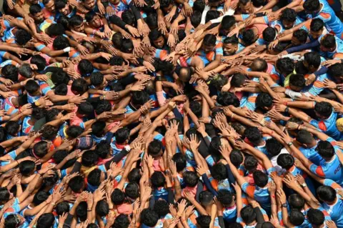 Getty Images Hindu devotees pray before forming a human pyramid to break a dahi-handi (curd-pot) suspended in the air during celebrations for the 'Janmashtami' festival, which marks the birth of Hindu god lord Krishna, in Mumbai on August 19, 2022. (