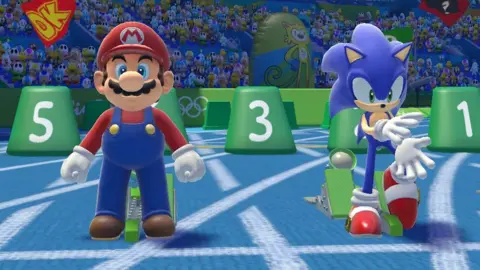 Nintendo A screenshot showing Mario and Sonic at the starting blocks on a light blue racetrack. Mario wears his trademark dungarees and Sonic his famous red sneakers. The two are getting ready to race, with a crowd made up of Nintendo and Sega sidekick characters looking on behind them.