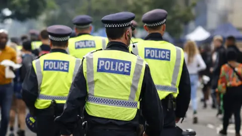 EPA Police officers wearing illuminous yellow tabards walk among the crowd at Notting Hill Carnival