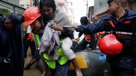 Reuters A police personal carries an injured woman from an inflatable raft after being rescued from a flooded area near the bank of the overflowing Bagmati River in Kathmandu, Nepal