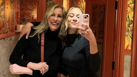 Alice Dallin Alice Dallin taking a selfie of herself and her mum Sarah Dallin in a bathroom. She has her arm around her mum and they are both smiling