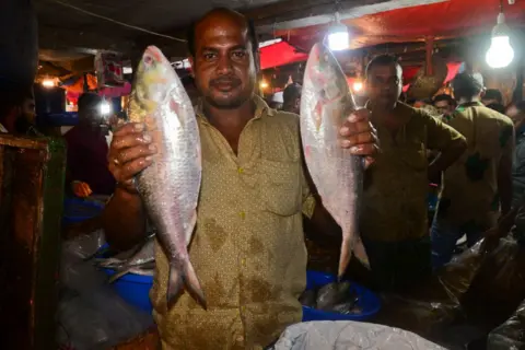 Getty Images Bangladeshi vendors show Hilsa fish for sell at the Karwan Bazar wholesale fish market in Dhaka, Bangladesh