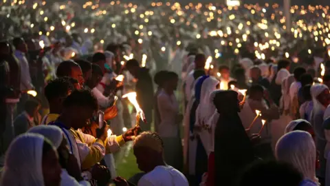 Amensisa Negera / BBC A crowd of worshippers hold lit torches