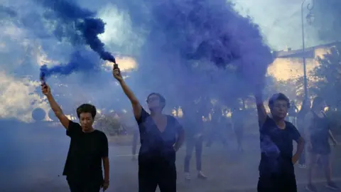 Christophe SIMON / AFP Demonstrators hold smoke bombs during a protest outside the courthouse during the trial of a man accused of drugging his wife Gisèle Pelicot for nearly 10 years and inviting strangers to rape her at their home in Mazan, a small town in the south of France, in Avignon, on September 2, 2024