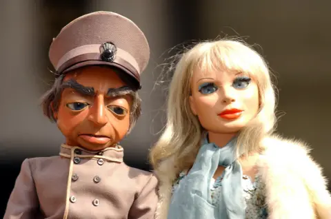 PA Parker and Lady Penelope in Thunderbirds - two puppets side by side, Parker in a chauffeur's uniform and Lady Penelope in blue sequins and fur