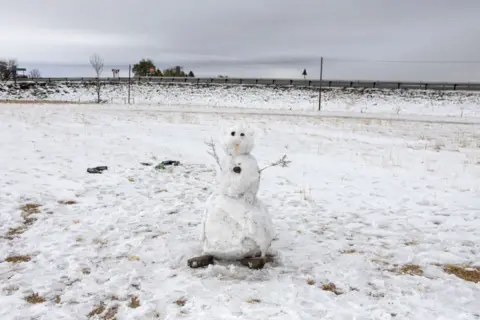 Wikus de Wet / AFP A photo shows a snowman on a snow covered sports field in Warden, Free State province, South Africa, on September 21, 2024.