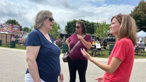 Ms Soucek (right) talks to Ms Conway (left) and other women voters about the economy