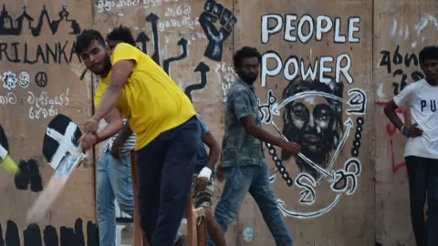 Getty Images Anti-government demonstrators play cricket at a protest camp tent near the Presidential Secretariat in Colombo on July 23, 2022. 