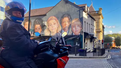 Tourist Isabelle Lang pictured on her motorcycle, infront of the Derry Girls mural.