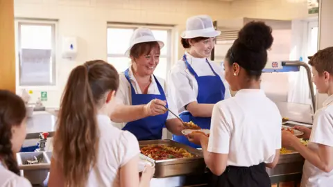 Getty Images School canteen staff dishing out meals to pupils